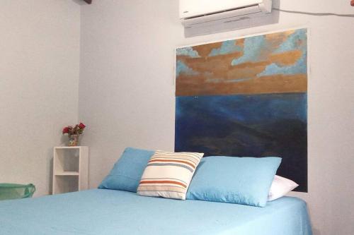 Un dormitorio con una cama azul con una pintura en la pared en Casa Pico Bonito, en El Porvenir