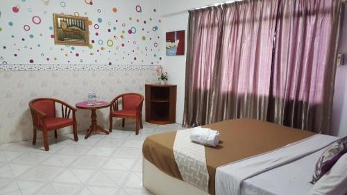 una camera con letto, tavolo e sedie di New Orchid Hotel Tuaran a Tuaran