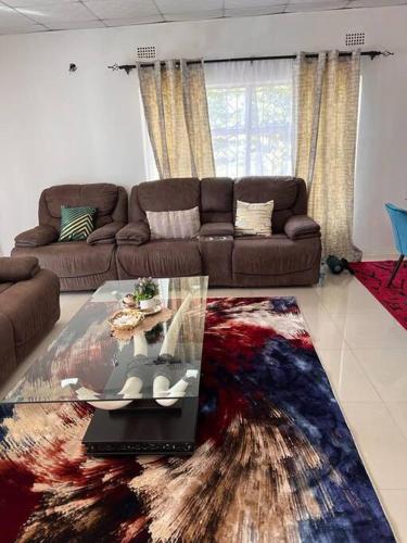 a living room with a couch and a glass table at Four m luxury Apartment. in Kitwe