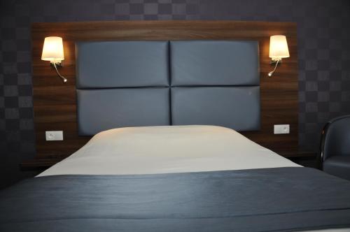 a bedroom with a bed and two lights on the wall at The Originals City, Hôtel et Restaurant Aster, Saint-Avold Nord in Creutzwald-la-Croix