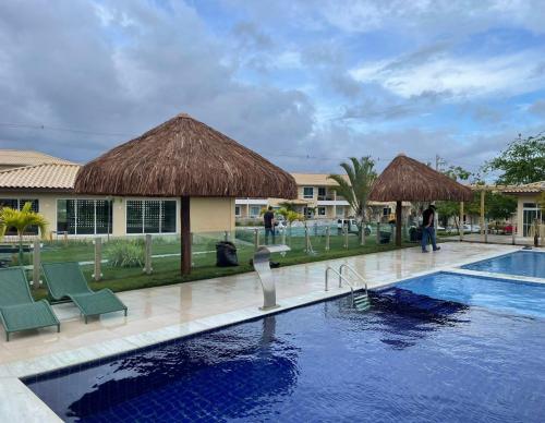 a resort with a swimming pool with chairs and a building at Condomínio encantador in Caruaru