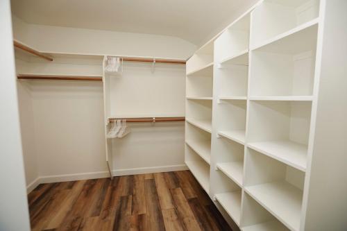 a walk in closet with white shelves and wood floors at Riverfront Beauty with Pickle Ball Court in Kingsburg