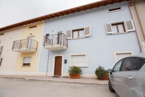 a white building with balconies and a car parked in front at Wolf House BnB in Coppito