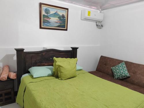 a bedroom with a bed with a green comforter at Gran Hotel Desamparados in Desamparados