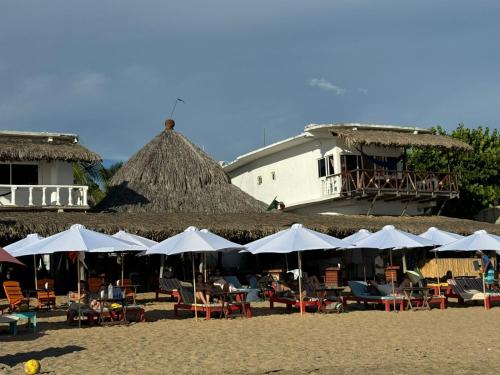 a group of tables and chairs with umbrellas on a beach at Che Zipolite Hostel & Beach Club in Zipolite