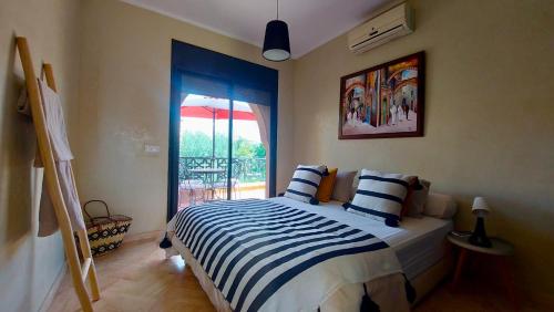 1 dormitorio con 1 cama con sábanas de rayas azules y blancas en Atlas Views By Golf Resort, en Marrakech
