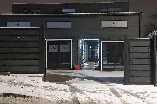 a black building with two doors and snow on the ground at okeyloft Coyhaique 5 in Coihaique