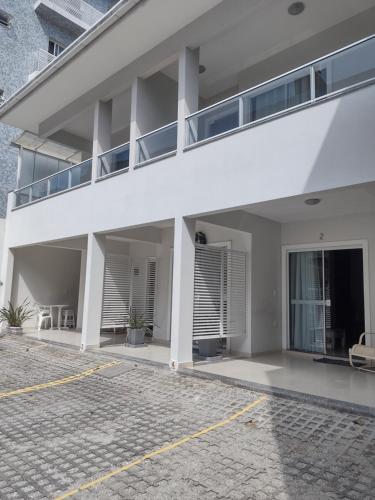 un edificio blanco con balcón y aparcamiento en Apartamentos próximo à praia, en Bombinhas