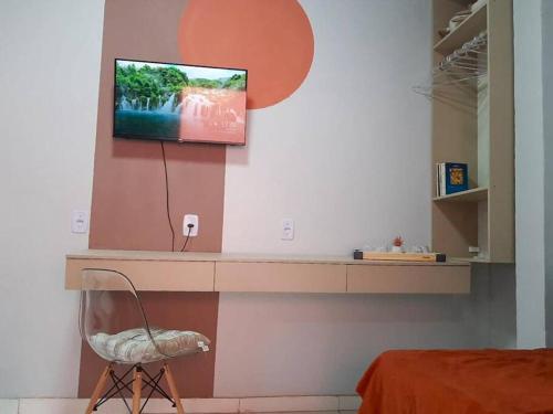 een kamer met een tv aan de muur met een stoel bij Apto com Varanda Próximo da Orla in Marabá