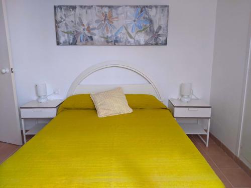 1 dormitorio con 1 cama amarilla y 2 mesitas de noche en Apartamento Playa, en S'Agaró