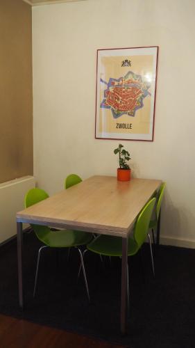 a wooden table with green chairs in an office at Het Zwolse Huisje in Zwolle