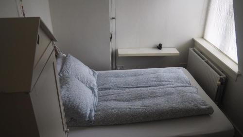 een kleine slaapkamer met een bed met een deken bij Het Zwolse Huisje in Zwolle