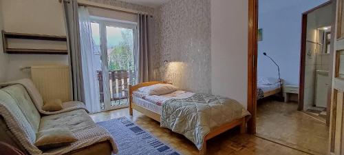 a bedroom with a bed and a chair and a window at Willa Potoki in Szklarska Poręba