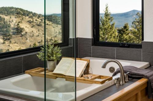 baño con bañera con libro y ventana en Stay in Evergreen - Denver Mountain Escape en Evergreen