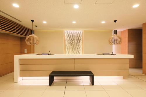 a lobby with a counter with a bench and two lights at Richmond Hotel Utsunomiya-ekimae Annex in Utsunomiya