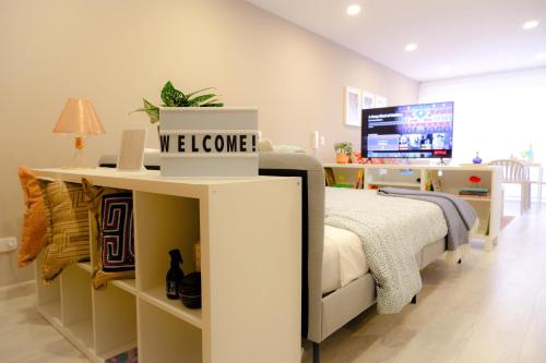 a bedroom with a bed with a welcome sign on it at The Petit Flat - Bright & stylish studio apartment near Unicentro in Bogotá