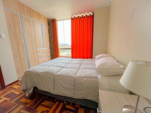 um quarto com uma cama e uma janela com cortinas vermelhas em Acogedor y lindo Departamento en estreno em Lima