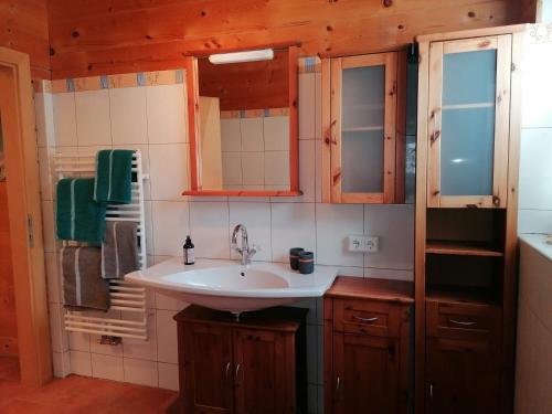 a bathroom with a white sink and wooden cabinets at Ferienwohnung Mireille in Oberperfuss