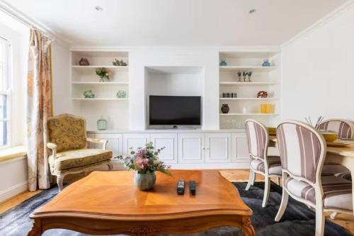 ein Wohnzimmer mit einem Tisch und einem TV in der Unterkunft Affordable, Secluded Flat in Central London in London