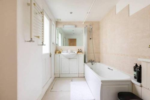 ein Badezimmer mit einer Badewanne, einem Waschbecken und einem Spiegel in der Unterkunft Affordable, Secluded Flat in Central London in London