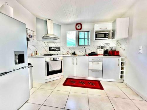 - une cuisine avec des appareils blancs et un tapis rouge au sol dans l'établissement Villa Dom's Evasion, à Sainte-Marie
