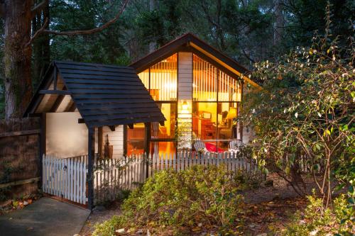 a small house in the woods with a fence at Cambridge Cottages in Olinda