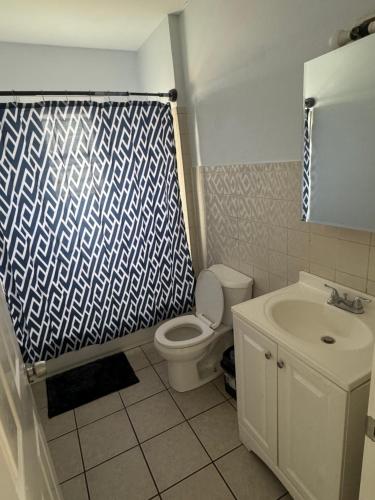 a bathroom with a toilet and a shower curtain at Cozy apartment nexttomain st in Passaic