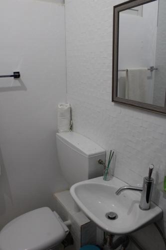 a white bathroom with a toilet and a sink at Suite Big Lanche in Praia Baixo
