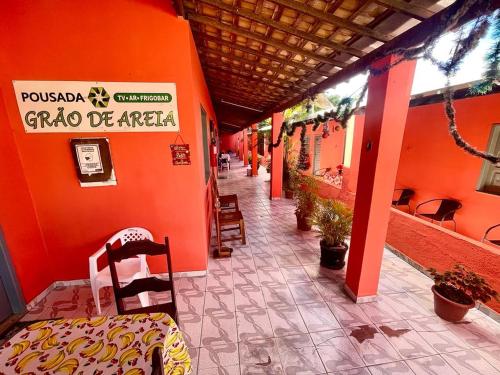 マンゲ・セッコにあるGraos de Areia Pioneiraのオレンジ色の壁の建物、椅子付きの廊下