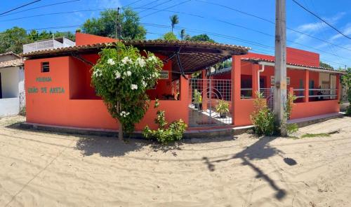 ein kleines orangenes Haus mit rotem Dach in der Unterkunft Graos de Areia Pioneira in Mangue Sêco