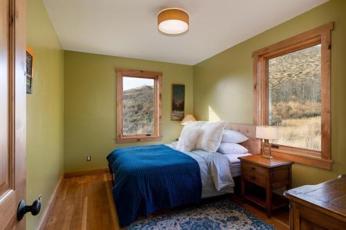 una camera da letto con un letto con una coperta blu e due finestre di Triumph Ranch Farm House ad Hailey