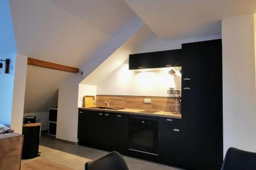 a kitchen with black cabinets and a sink at Magnifique appartement au pied des pistes - Le trelod in La Féclaz