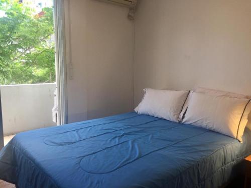 uma cama com um cobertor azul e uma janela em Artistes du Monde em Montevidéu