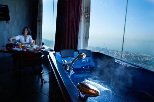 a woman sitting at a table in a bathroom with a tub at Bay Lodge Boutique Hotel in Jounieh