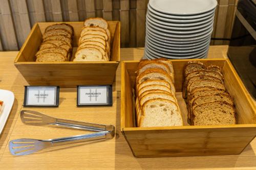 two wooden trays of bread on a table with plates at M382 Hotel Bariloche in San Carlos de Bariloche