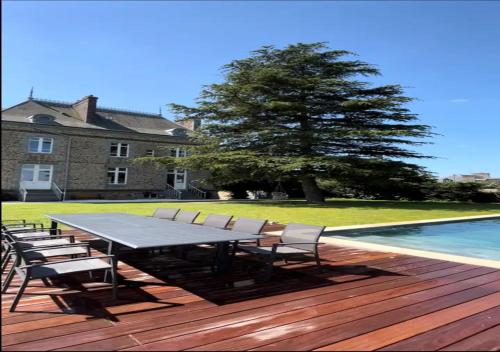 - une table et des chaises sur une terrasse à côté de la piscine dans l'établissement Le Manoir Ducey - Baie du Mont-Saint-Michel, à Ducey