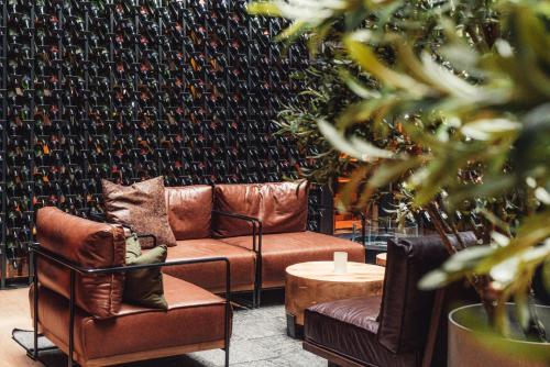 um quarto com duas cadeiras de couro e uma parede de garrafas de vinho em Magic Hotel & Apartments Kløverhuset em Bergen