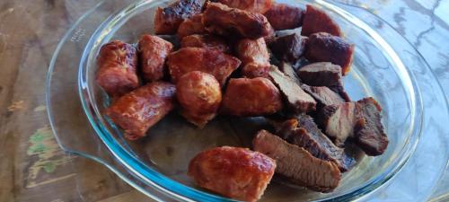 a glass bowl filled with bacon and meat on a table at Casa de praia Guarau in Peruíbe
