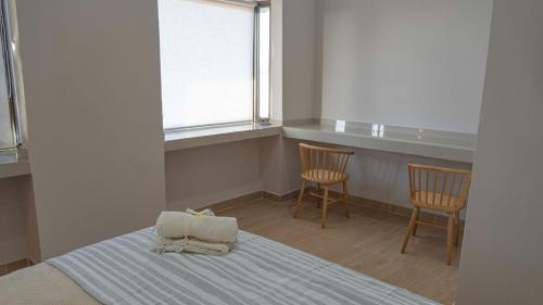 a bedroom with a bed with two chairs and a window at Hotel La Casona del Desierto in Huasco