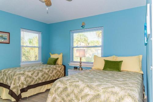twee bedden in een kamer met blauwe muren en ramen bij Magnolia Breeze in Anna Maria