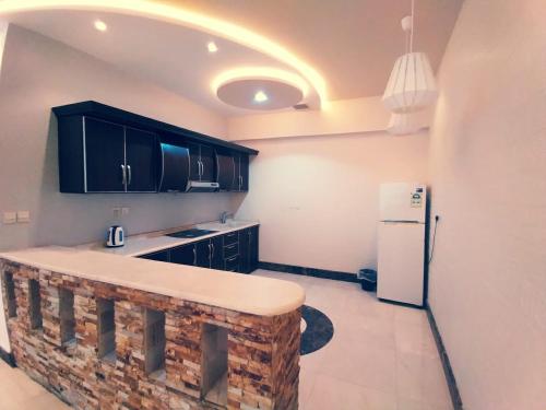 uma cozinha com armários pretos e um frigorífico branco em شاليهات الكوخ السويسري وأكوابارك em Ash Shishah