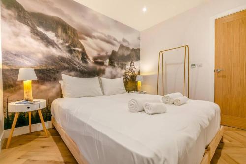 a bedroom with a large white bed with a painting on the wall at Luxury holiday home near the coast in Porthtowan