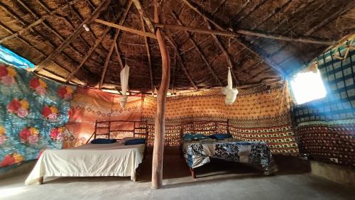 een kamer met 2 bedden en een rieten dak bij Campement Kaymba Lodge in Kachiouane