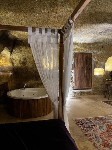 a bedroom with a tub and a bed with a curtain at Chakra Special Caves in Ürgüp