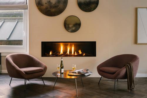 een woonkamer met 2 stoelen en een open haard bij Sonder Park House in Amsterdam