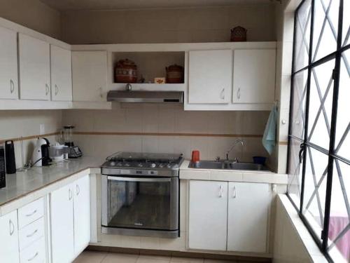 a kitchen with white cabinets and a stove and a sink at Foro sol autódromo aeropuerto in Mexico City