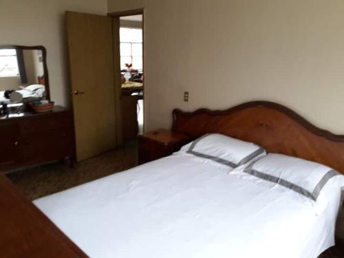 1 dormitorio con cama blanca y cabecero de madera en Foro sol autódromo aeropuerto, en Ciudad de México