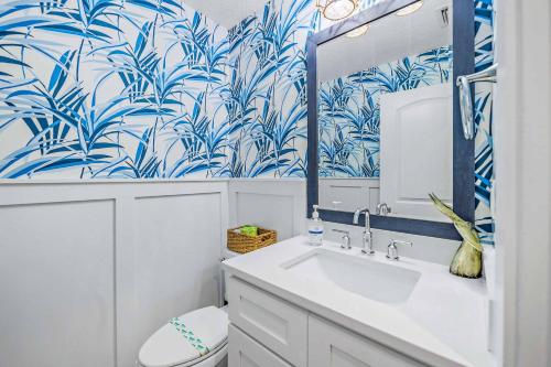 La salle de bains est pourvue d'un lavabo blanc et de papier peint bleu et blanc. dans l'établissement The Beach Front, à Holmes Beach