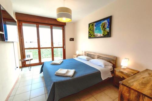 a bedroom with a blue bed in a room with windows at Appartamento Mango in Cavallino-Treporti