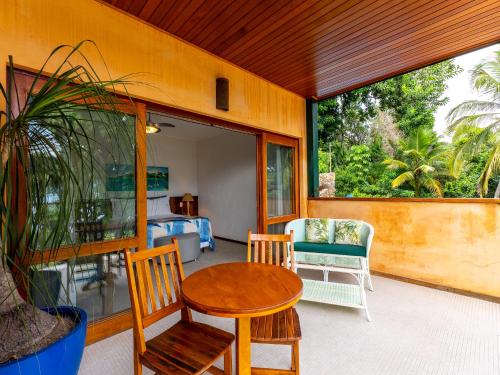 a porch with a table and chairs and a bedroom at Hotel Velas do Engenho in Ilhabela